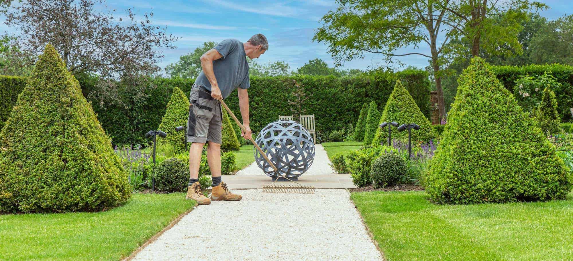 landscape contractors for garden designers showing man raking pathway