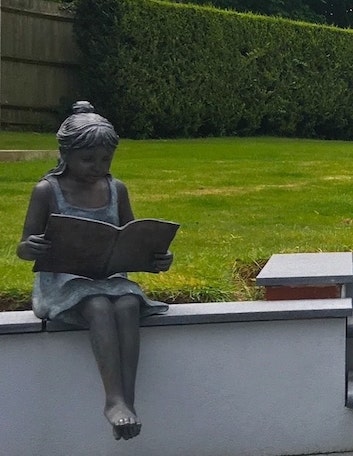 paving installers surrey and west sussex showing girl reading book sculpture